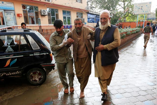 Men carry an injured person to a hospital after the bomb blast rocked the mosque in the Nangarhar Province