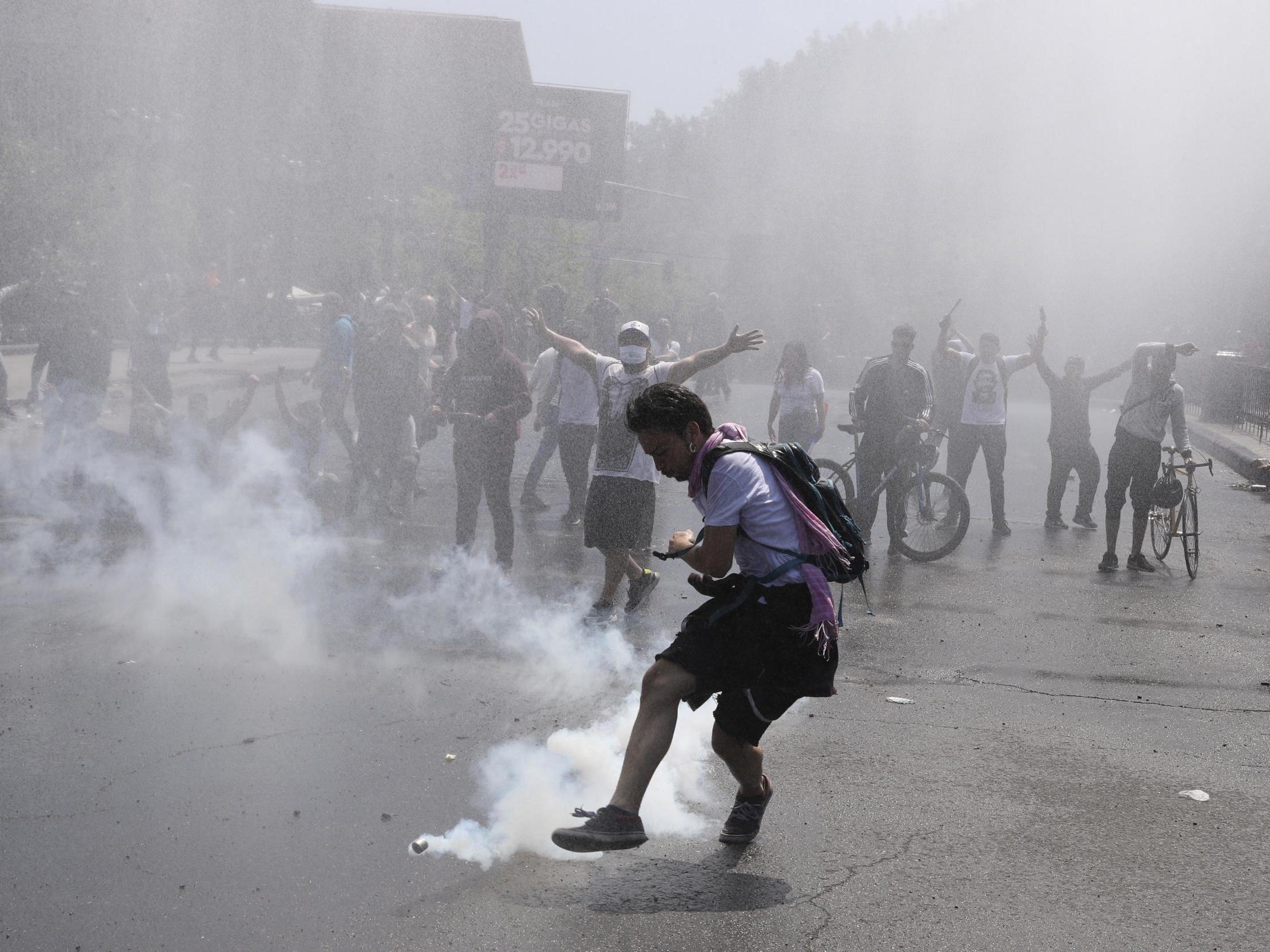 A protester kicks a tear gas canister during clashes in Santiago