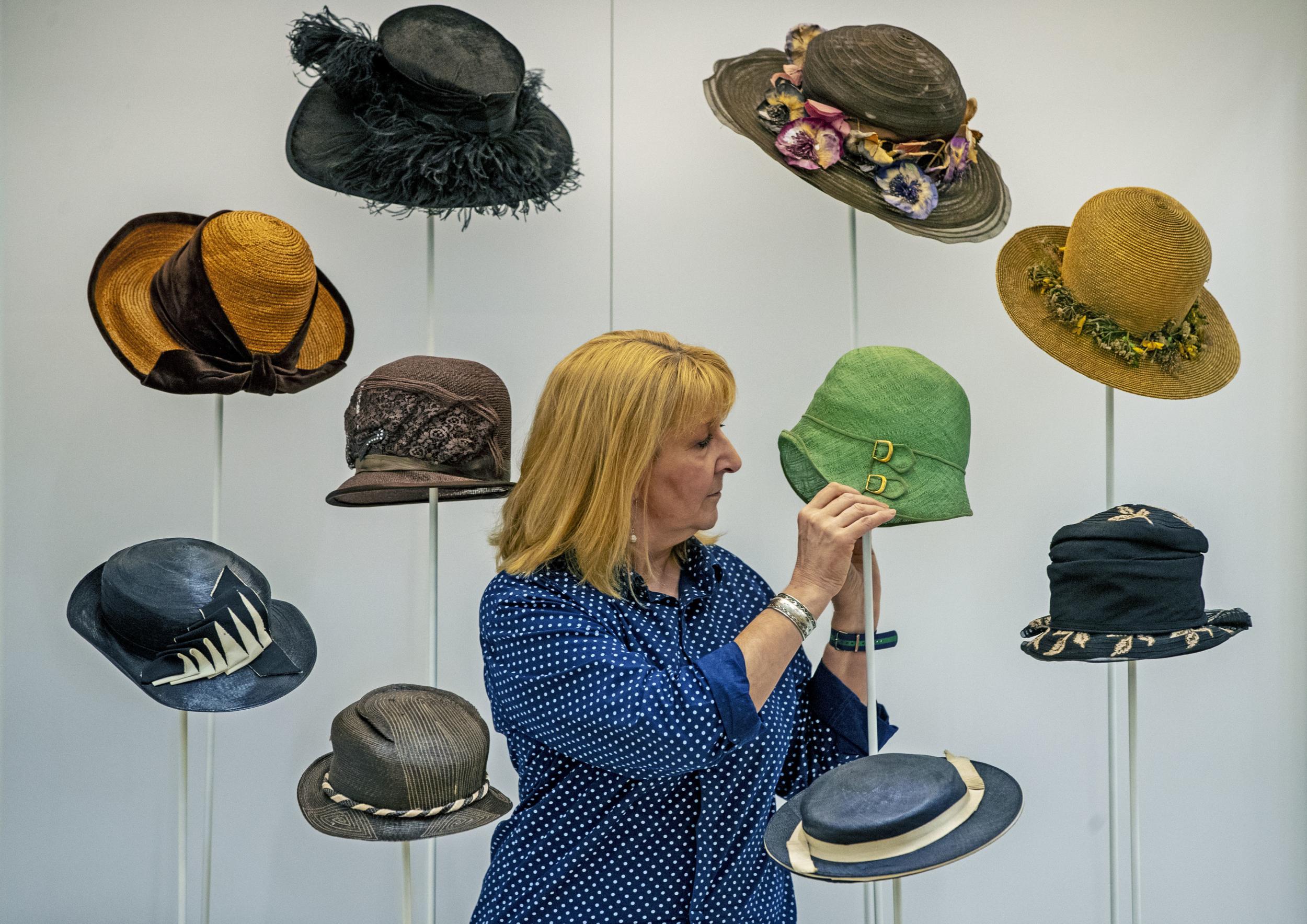 Curator Pauline Rushton examines one of Emily Margaret Tinne's many hats