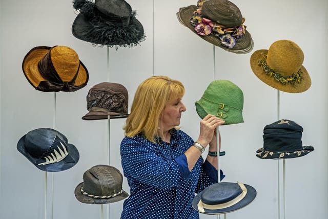  Curator Pauline Rushton examines one of Emily Margaret Tinne's many hats