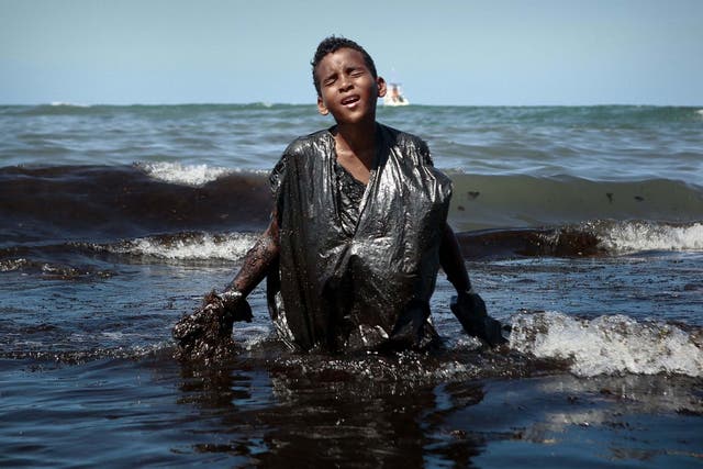 A boy removes oil spilled on Itapuama beach in the state of Pernambuco, Brazil