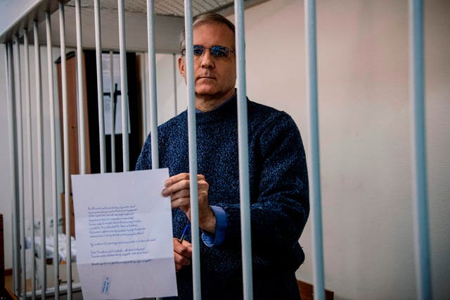 Paul Whelan holds a message as he stands inside a defendants' cage before his latest hearing in Moscow