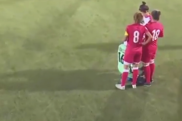 Female football players huddle around opponent after hijab slips during game