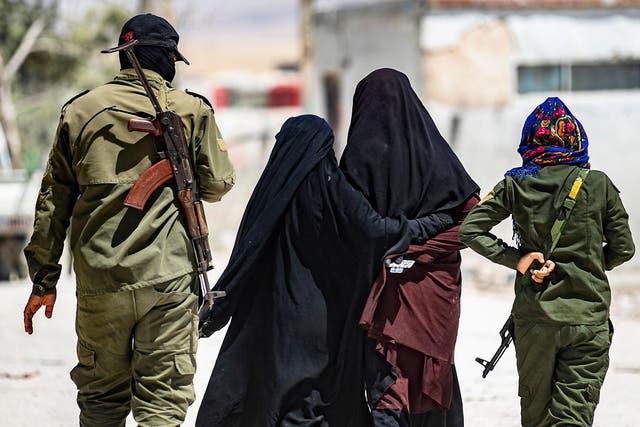 An internal security patrol escorts women, reportedly wives of Islamic State (IS) group fighters, in the al-Hol camp in al-Hasakeh governorate in northeastern Syria