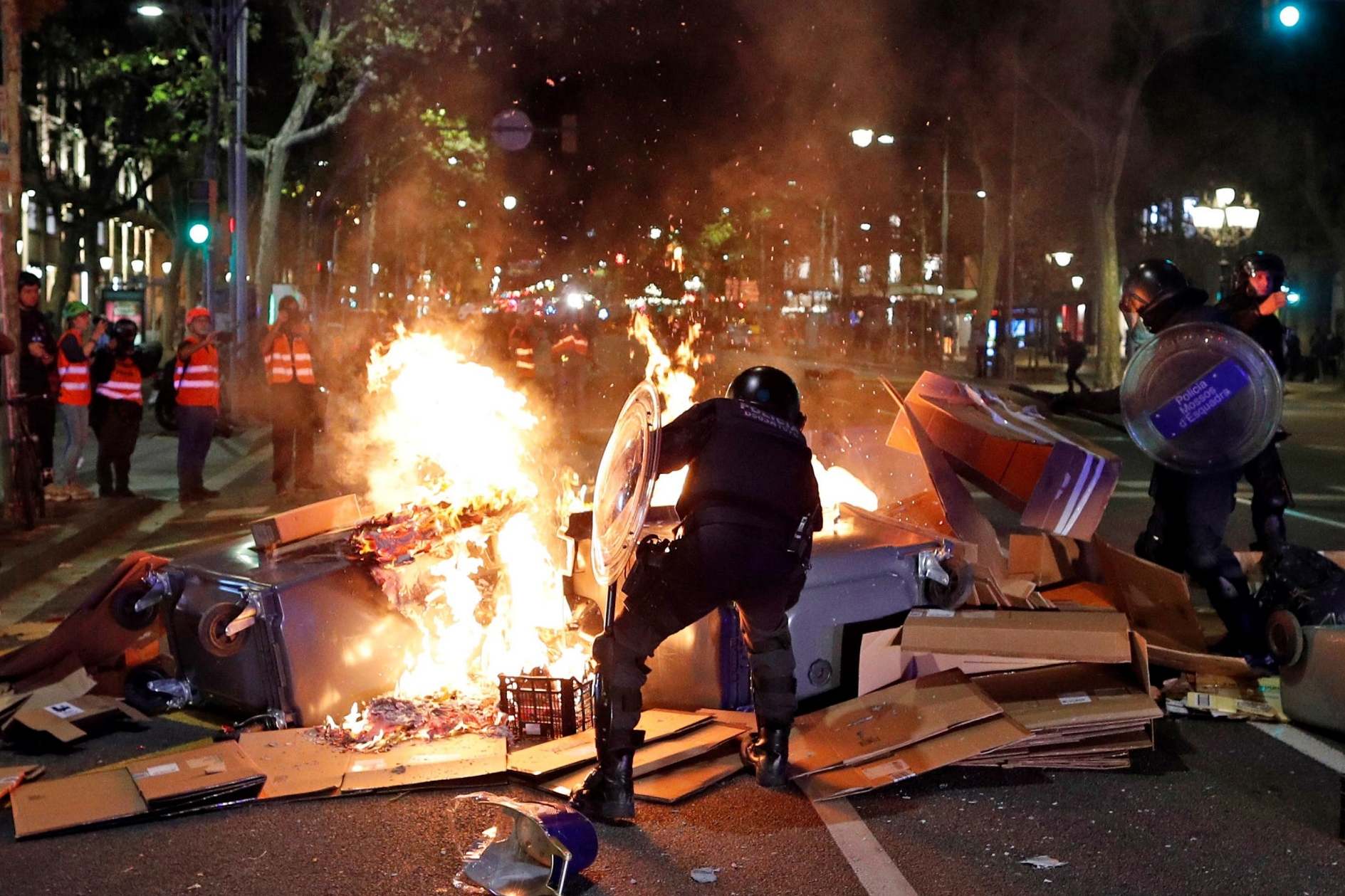 Riot police members try to put out the fire of a barricade during a protest in Barcelona