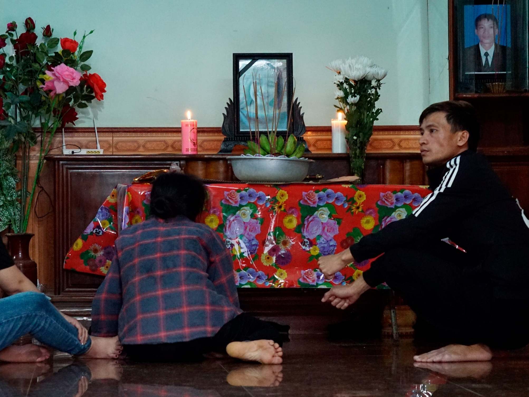 The mother, left, and other relatives of Bui Thi Nhung sit in front of an altar inside her home (AP)