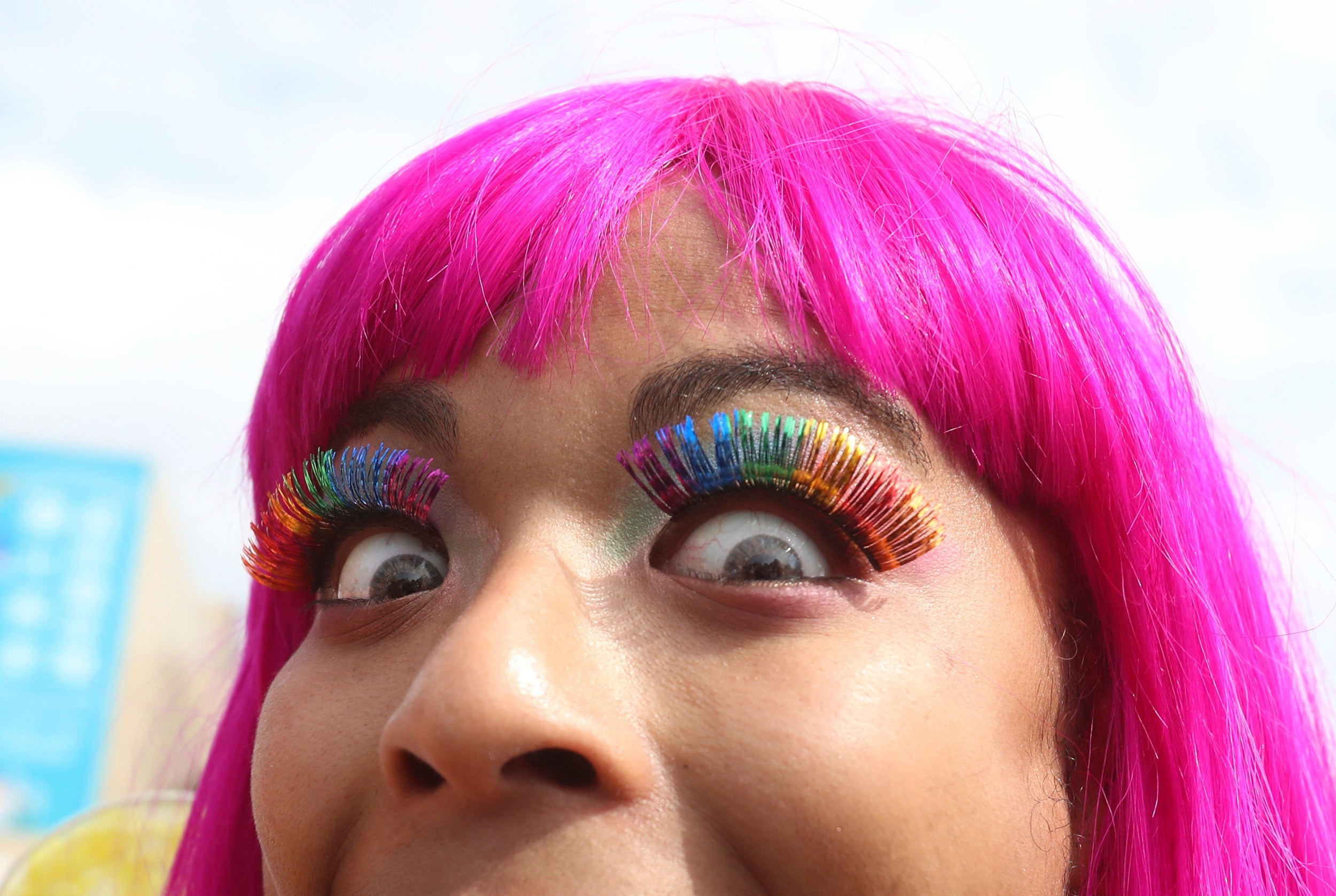 A reveller shows off their striking, rainbow-coloured eyelashes