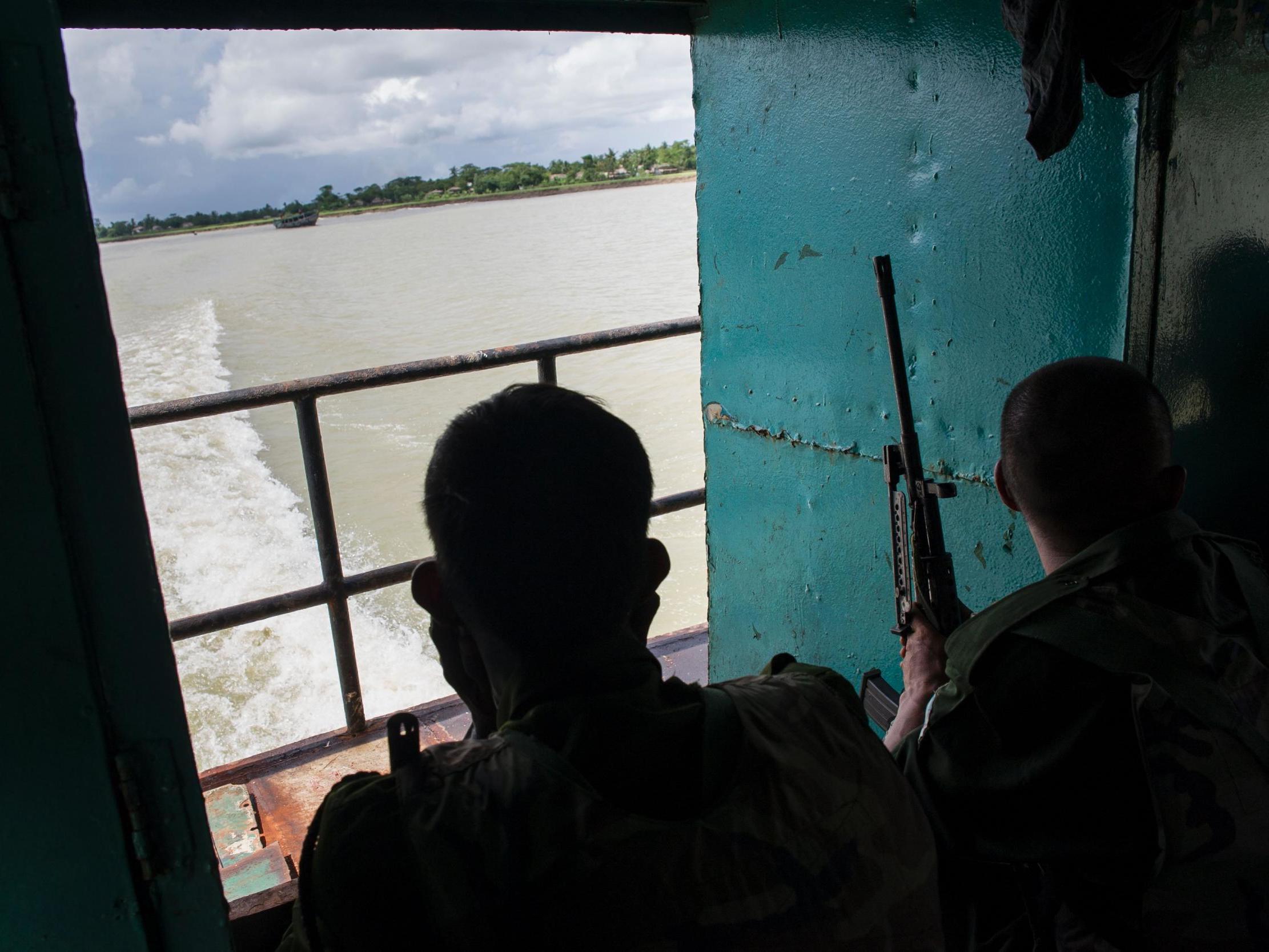 Myanmar soldiers ride on a boat travelling in Myanmar's Rakhine State