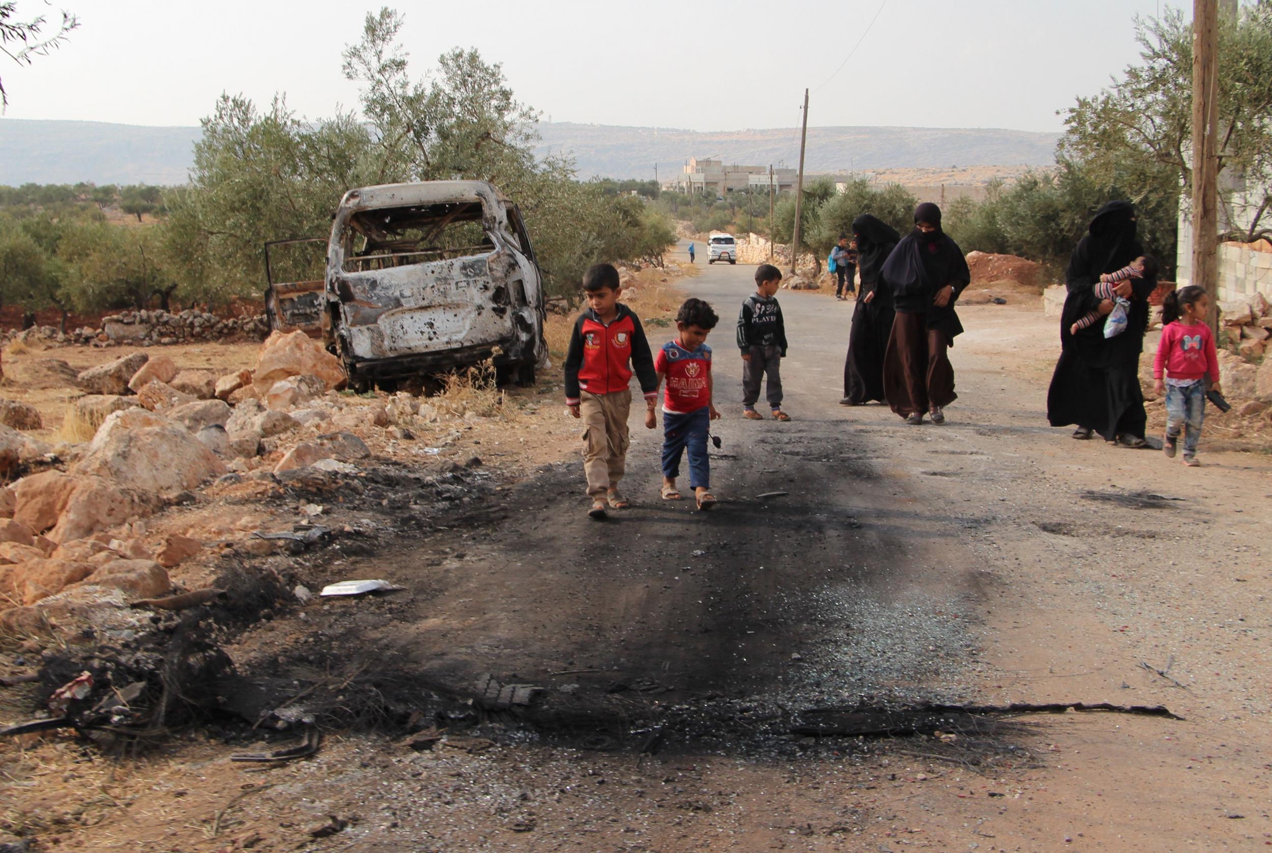 Locals walk past a damaged van at the alleged site where Isis leader was killed