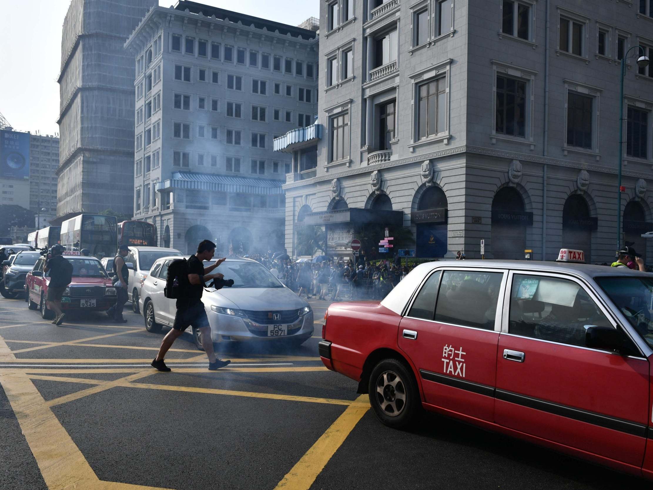 Photographers react after police fire tear gas outside the Peninsula Hong Kong on 27 October