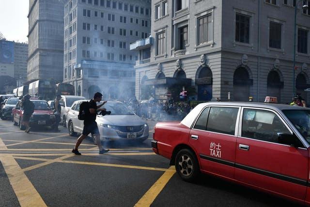 Photographers react after police fire tear gas outside the Peninsula Hong Kong on 27 October
