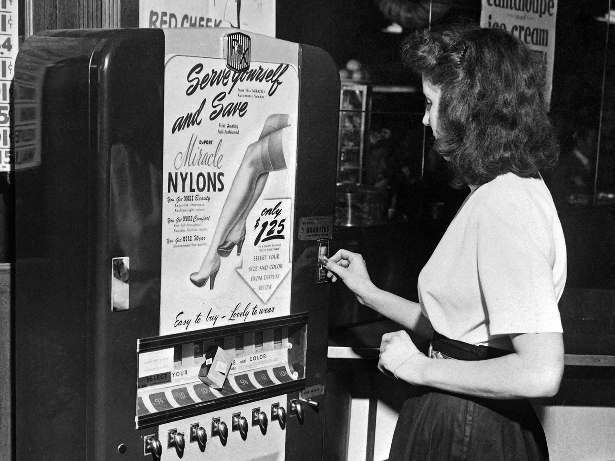 A young woman buys nylon stockings from an automatic vending machine in a New York restaurant in 1946