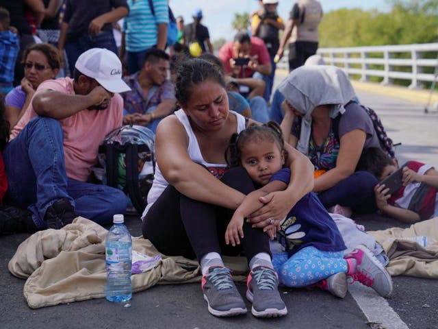 A woman from Honduras holds her three-year old daughter as she sits with a group blocking the Puerta Mexico international border crossing bridge to demand quickness in their asylum process