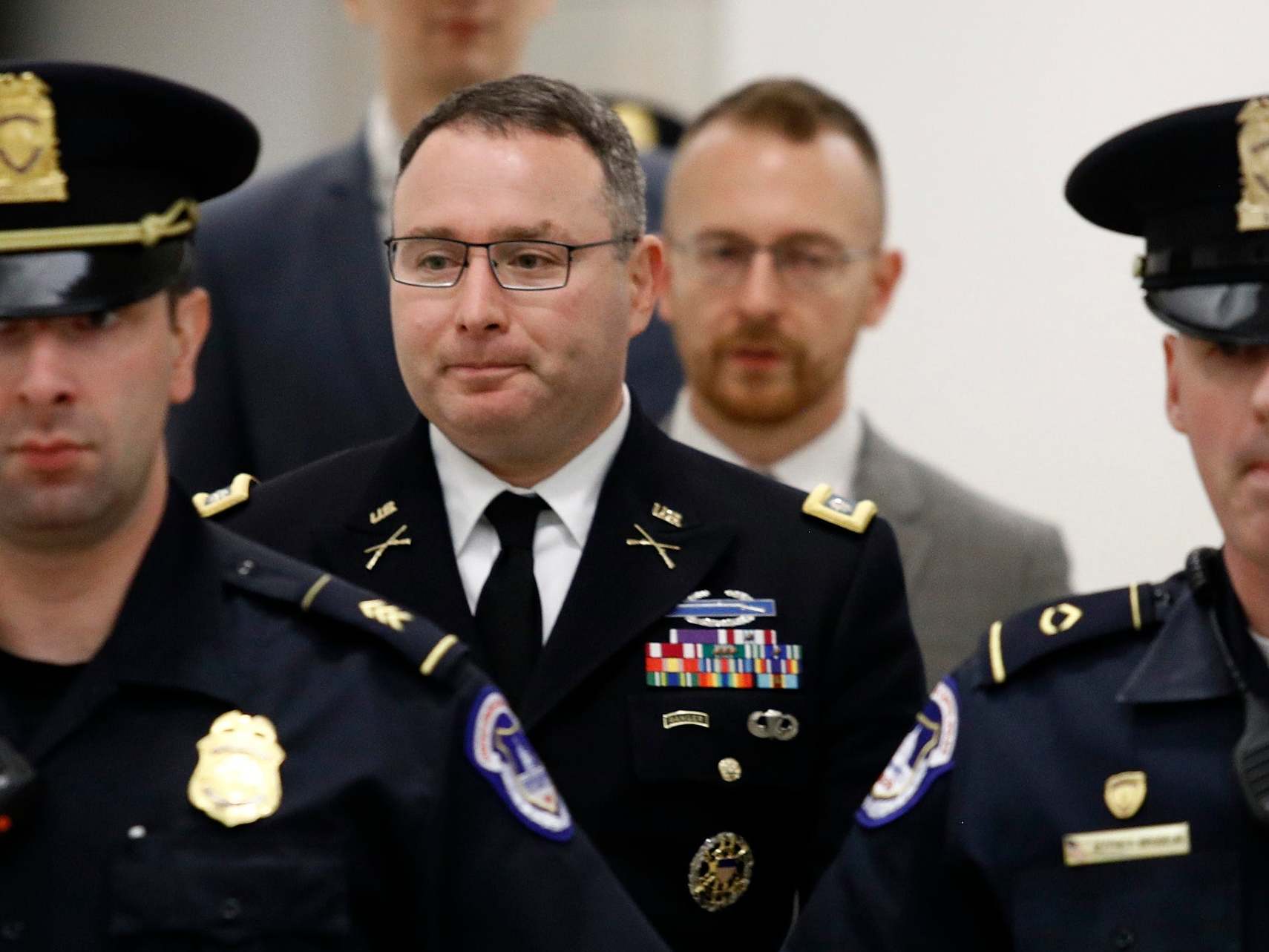 Lt Col Alexander Vindman, second left, leaves a closed-door meeting after testifying for 10 hours as part of the impeachment inquiry into Donald Trump