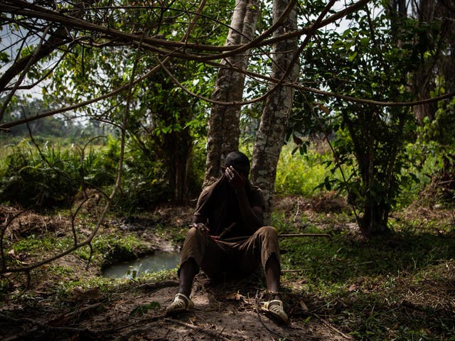 Abou Traore, 15, from Burkina Faso, sits against a tree drying the sweat on his face with his t-shirt on a cocoa farm near the village of Niambly, Ivory Coast