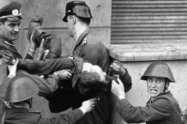A bloodied and dying Fechter is carried away by the East German guards who shot him down as he tried to flee to the west