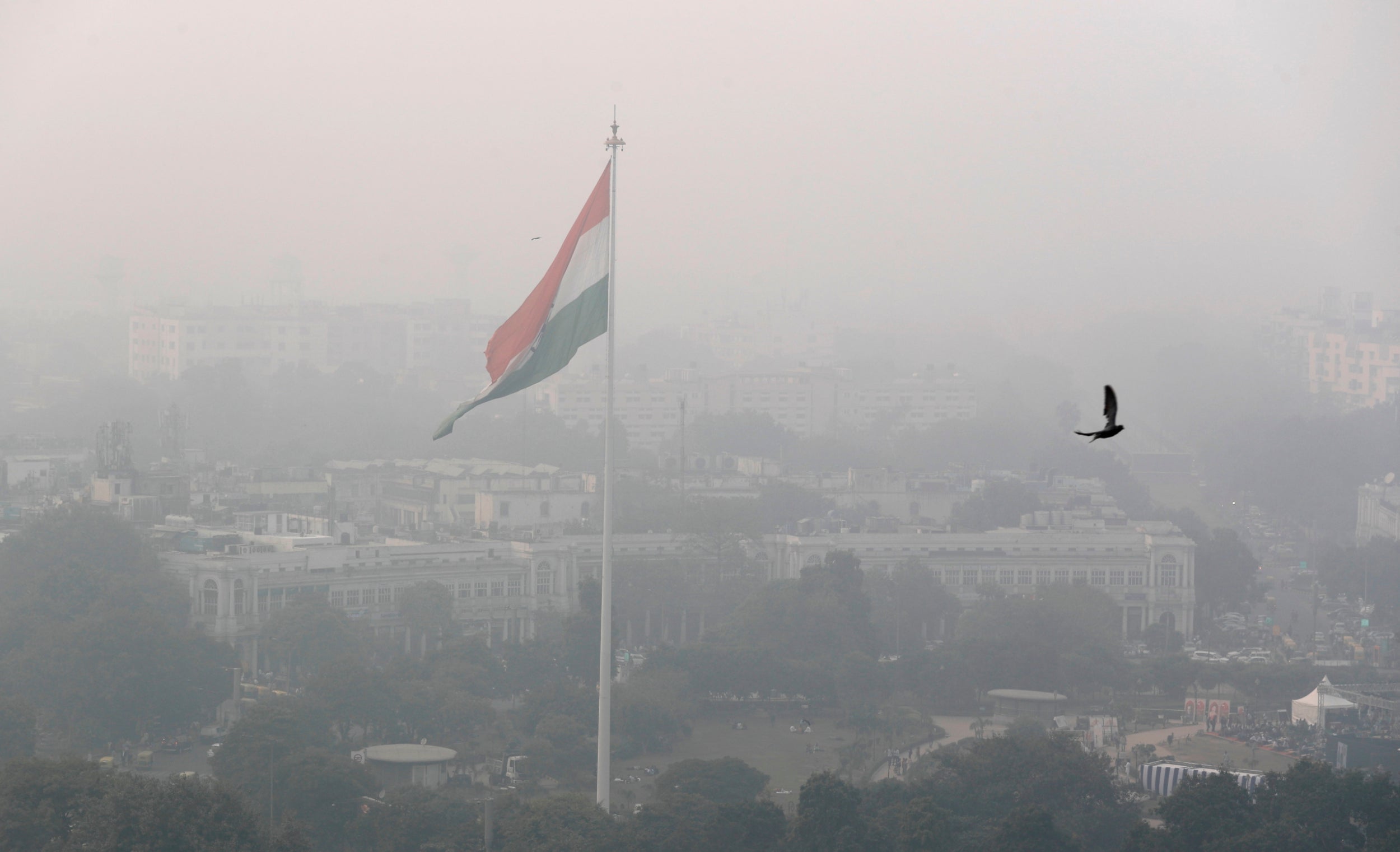 A bird flies past as Delhi’s skyline is seen enveloped in smog and dust on Friday