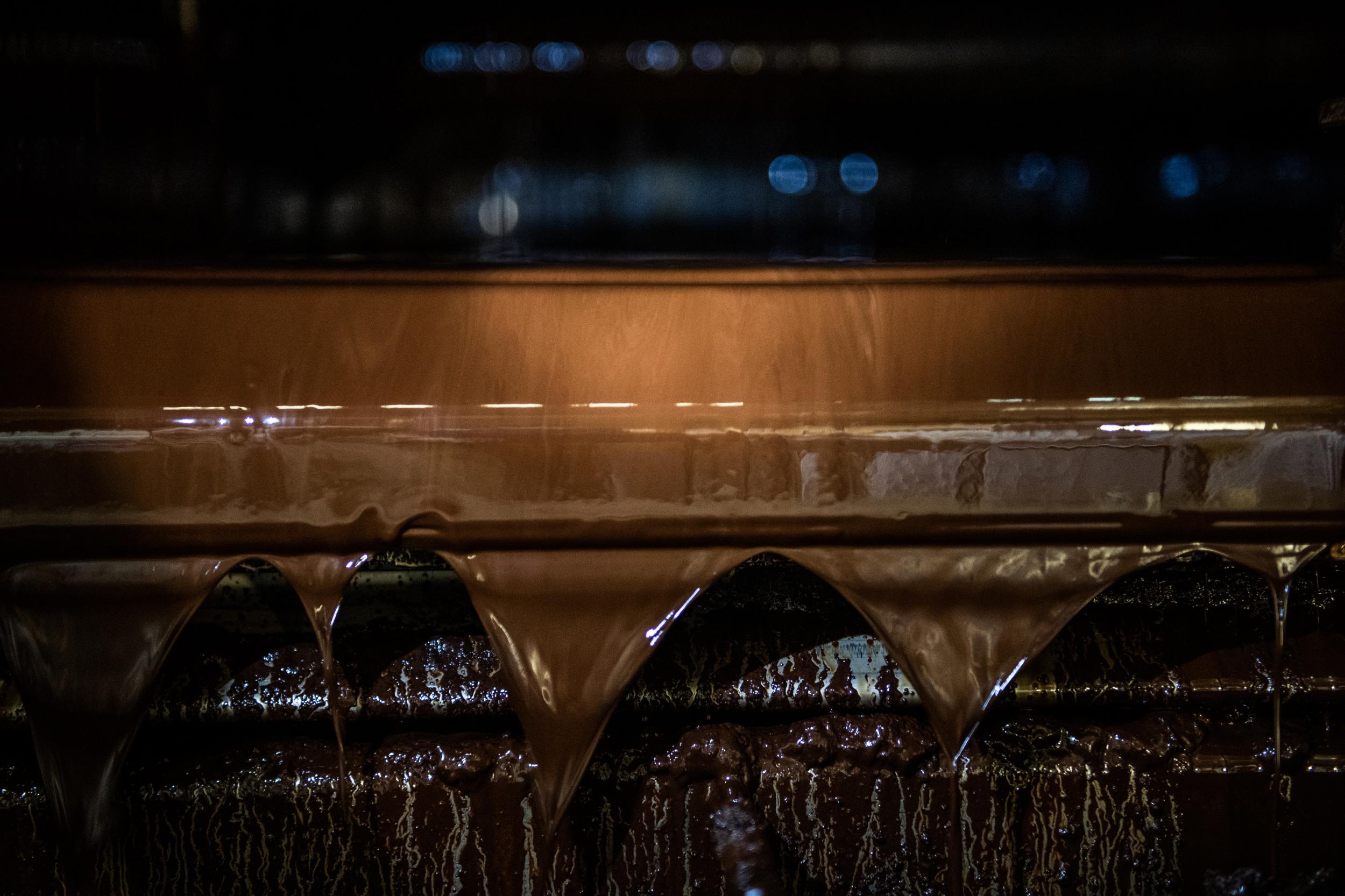 A stream of melted chocolate runs along a piece of equipment at the Mars factory