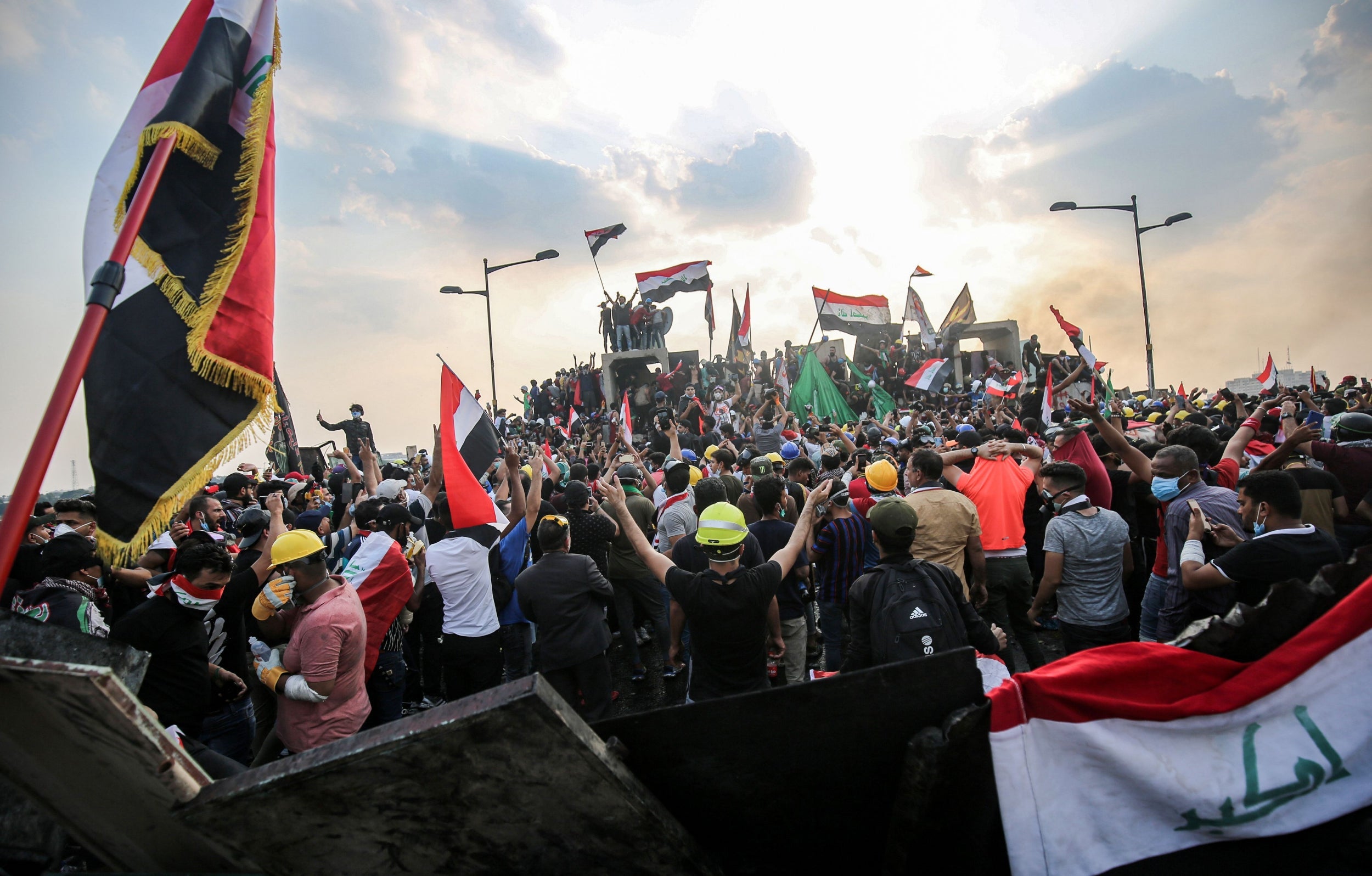 Iraqi protesters wave national flags across Baghdad's al-Jumhuriya bridge (AFP/Getty )