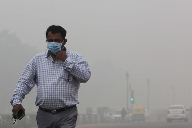 A resident of New Delhi walks with a face mask as smog envelops the city