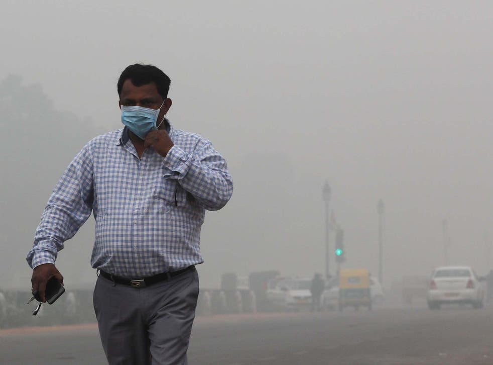 A resident of New Delhi walks with a face mask as smog envelops the city