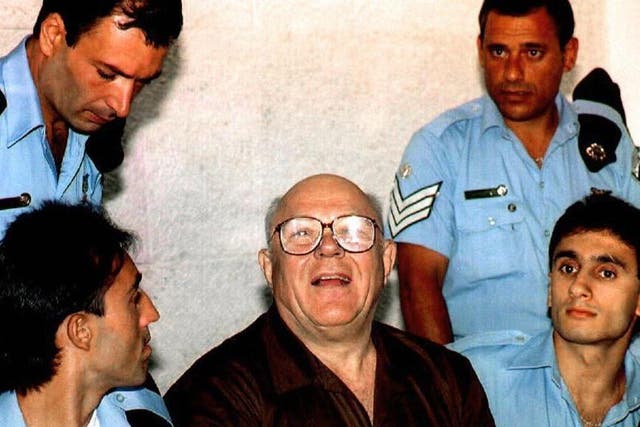 John Demjanjuk surrounded by guards at his Israeli trial for war crimes