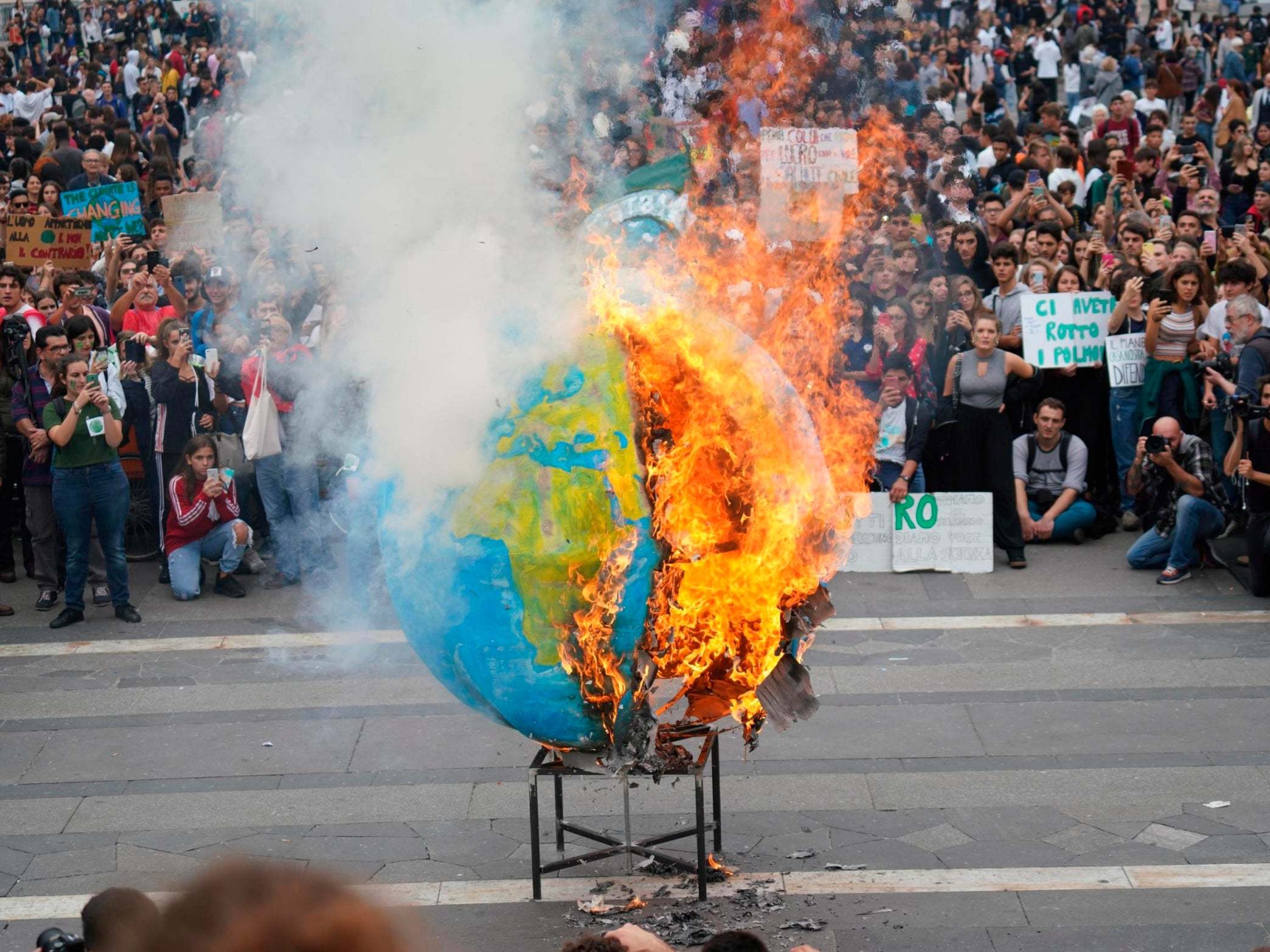 Students set fire to a model of Earth in Milan during a worldwide protest demanding action on climate change