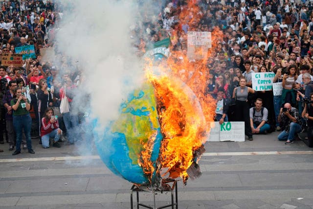 Students set fire to a model of Earth in Milan during a worldwide protest demanding action on climate change