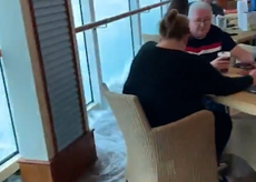 Cruise passengers calmly carry on drinking as water floods across deck