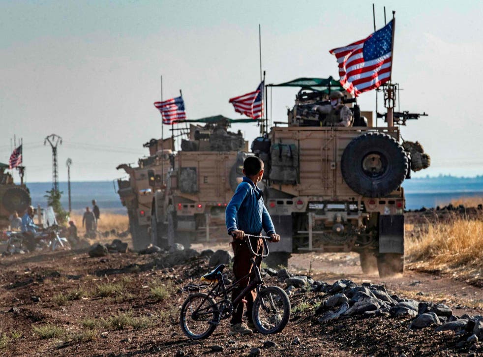 Syrian boy looks at US vehicles patrolling fields near the town of Qahtaniyah, October 2019