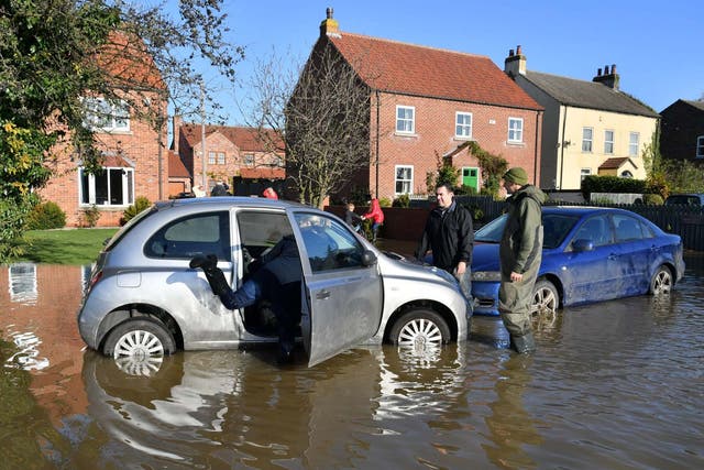 Adele Croucher pours water from her Wellington boots before getting into her daughter's car to remove it from floodwater