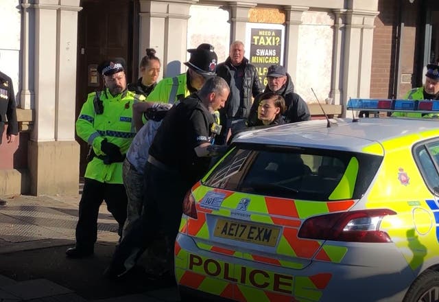A man is bundled away by police  to protect him from the angry after he disrupted a silent tribute with fireworks at a Remembrance Sunday event at the cenotaph in Eccles, Salford