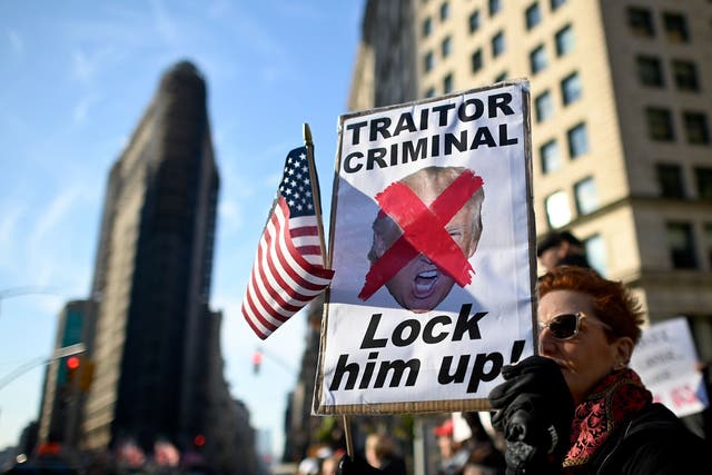 A protester holding a sign reading 'Traitor, Criminal, Lock him up!' close to where President Donald Trump is giving a speech at Madison Square Park in New York City to mark Veterans Day