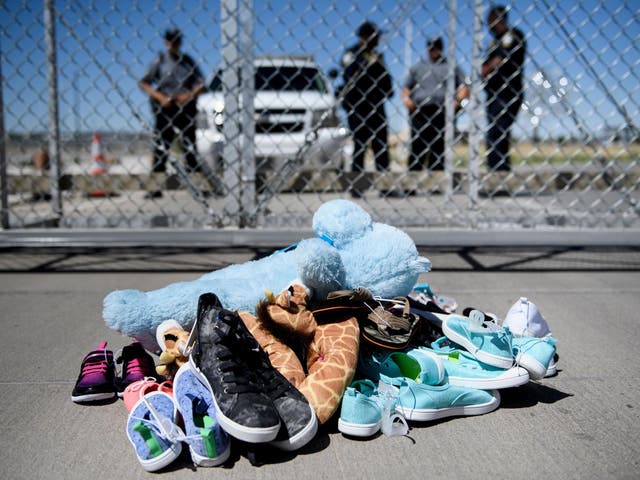 Security personnel stand before shoes and toys left at the Tornillo Port of Entry where children crossing the border without proper papers have been housed after being separated from adults