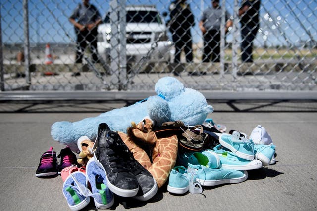 Security personnel stand before shoes and toys left at the Tornillo Port of Entry where children crossing the border without proper papers have been housed after being separated from adults