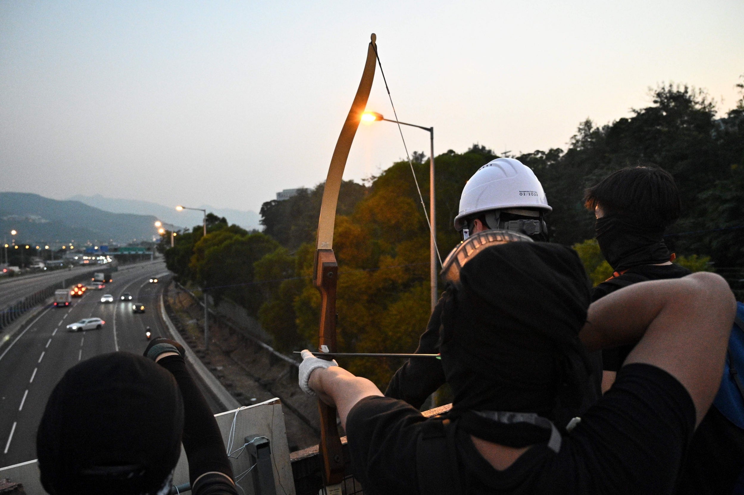 A protester with a bow and arrow aims out at the Tolo Highway outside the Chinese University of Hong Kong (CUHK), in Hong Kong on Wednesday