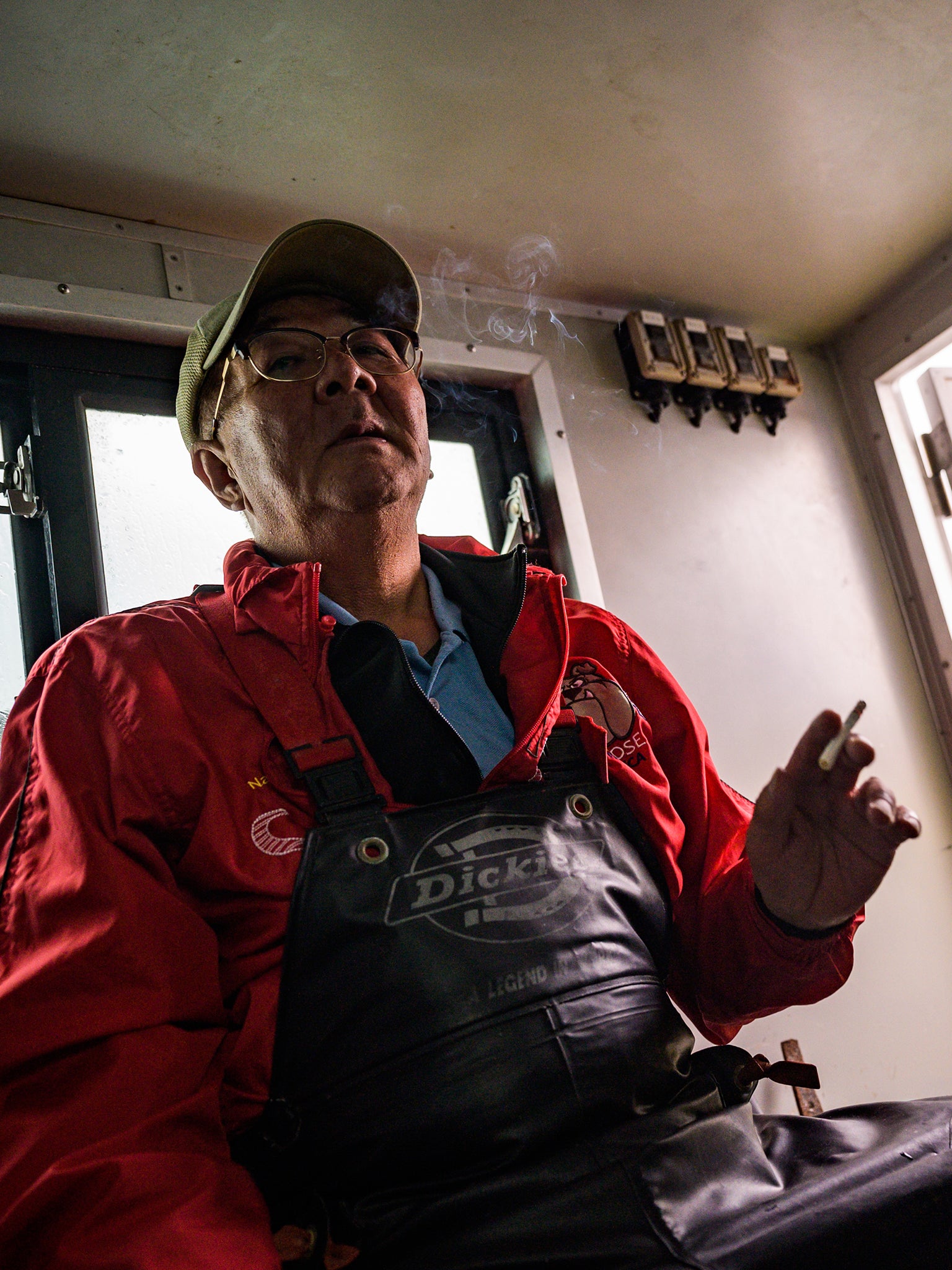 Nobuo Sugimura, 63, smokes a cigarette as he and other fishermen on the Hokushin Maru ship head back after catching salmon from the Sea of Okhotsk