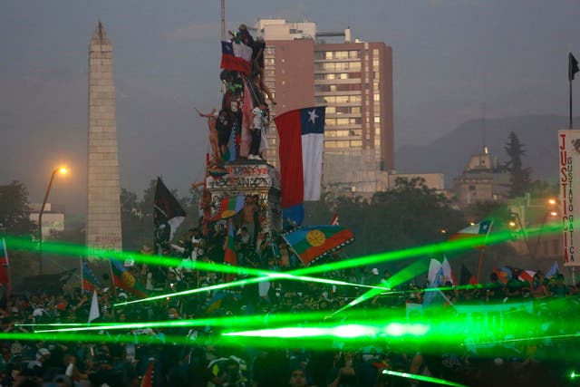 Demonstrators take on riot police using green laser lights in Santiago, Chile, on 15 November