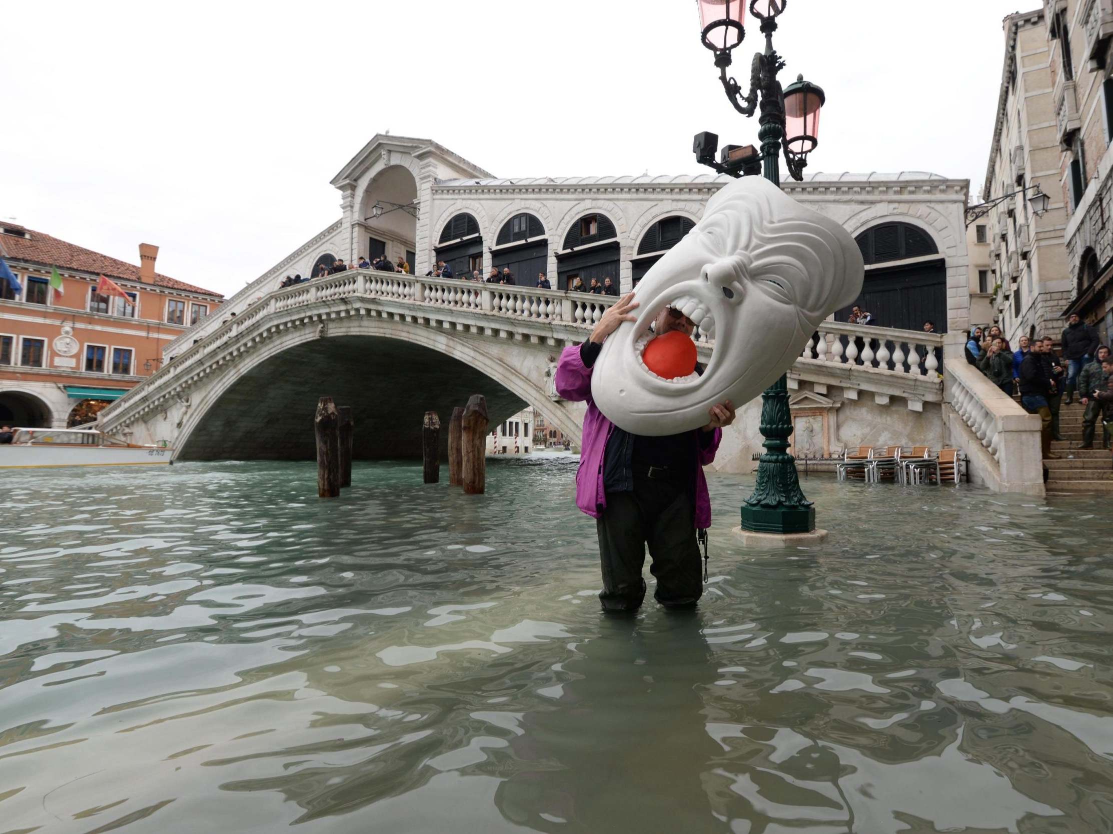 A tourist holds a huge mask amid rising water levels in Venice on 17 November