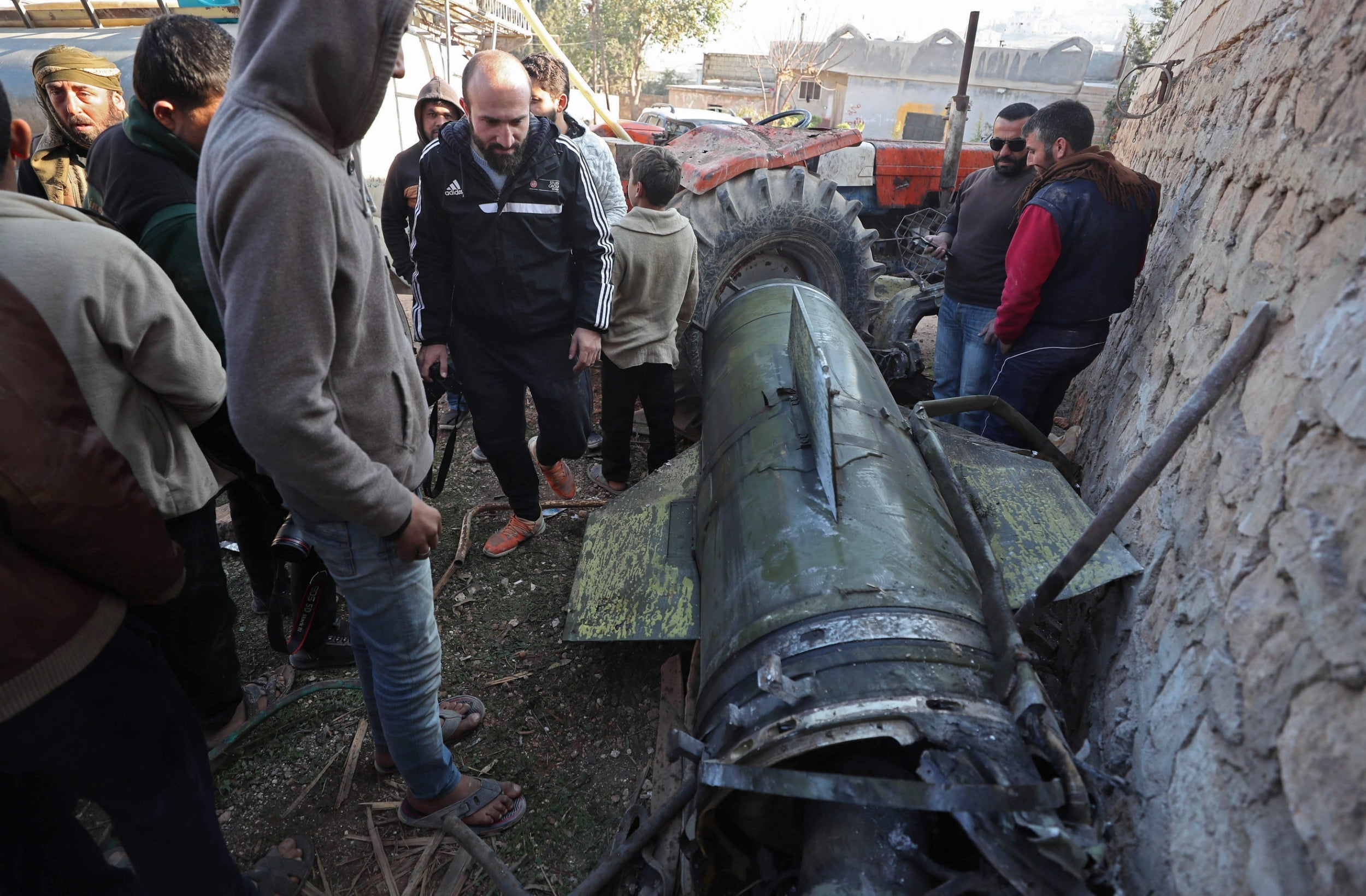 Civilians gather next to a fragment of a ground-to-ground missile fired by Syrian regime forces