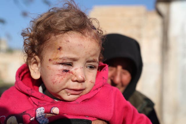 A woman holds an injured girl by last night's Syrian regime bombardment on a makeshift camp in the village of Qah near the Turkish border in the northwestern Idlib province
