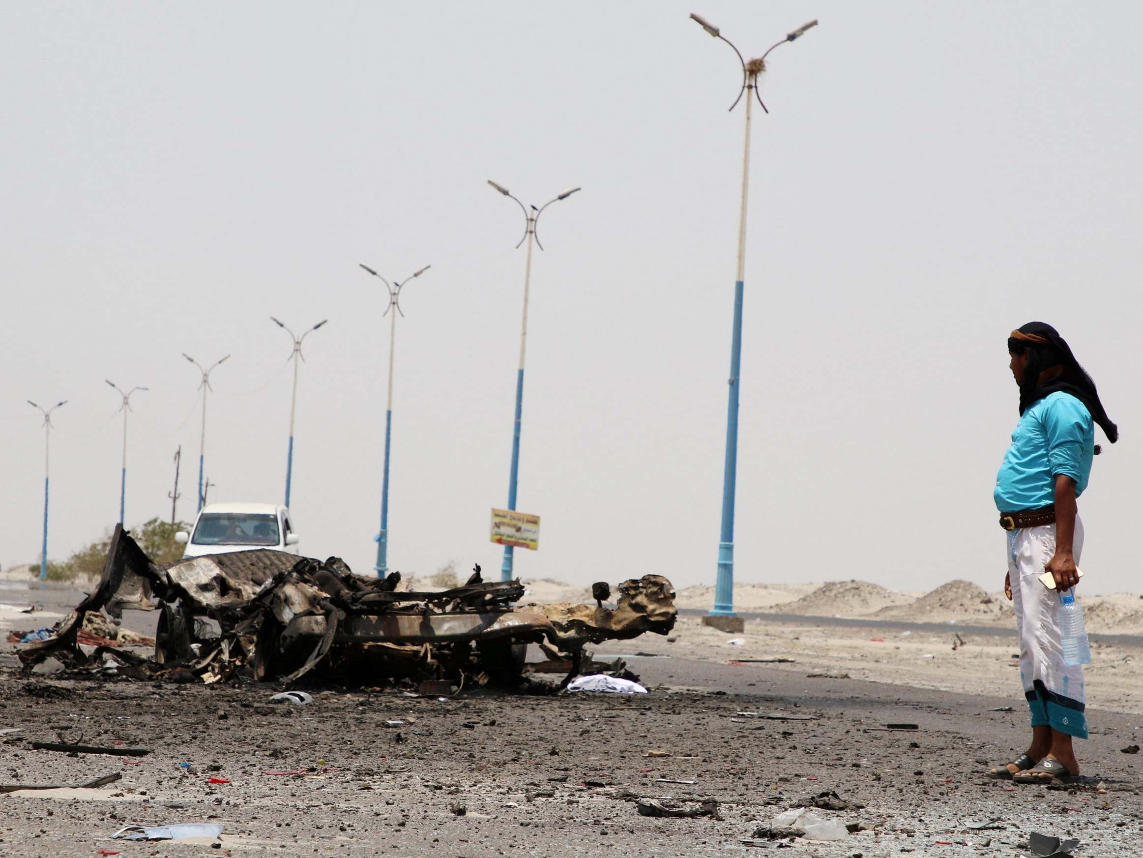 A man stands past the wreckage of government forces vehicles destroyed by UAE air strikes near Aden, Yemen, August 30, 2019