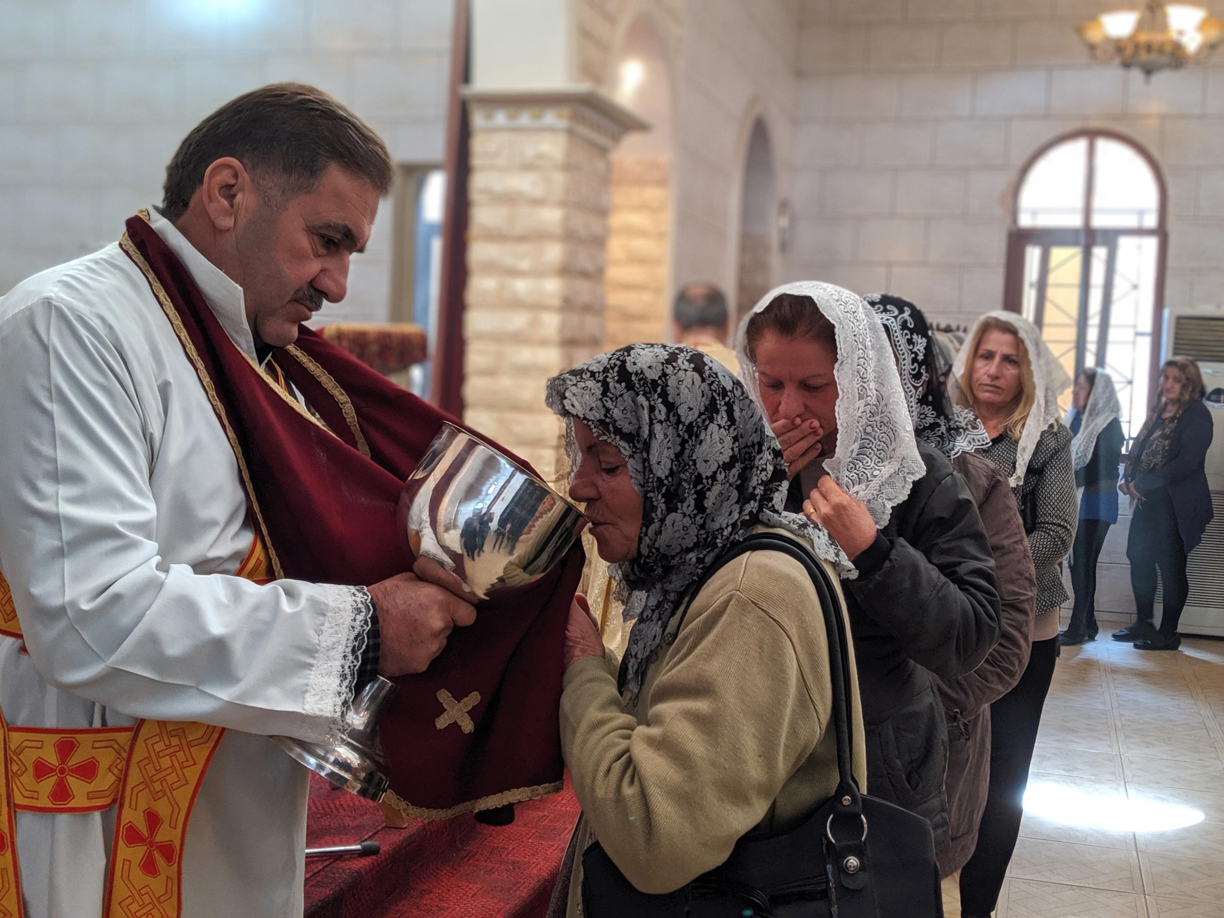 A woman takes communion at a church in Tal Tamr (Richard Hall/The Independent)