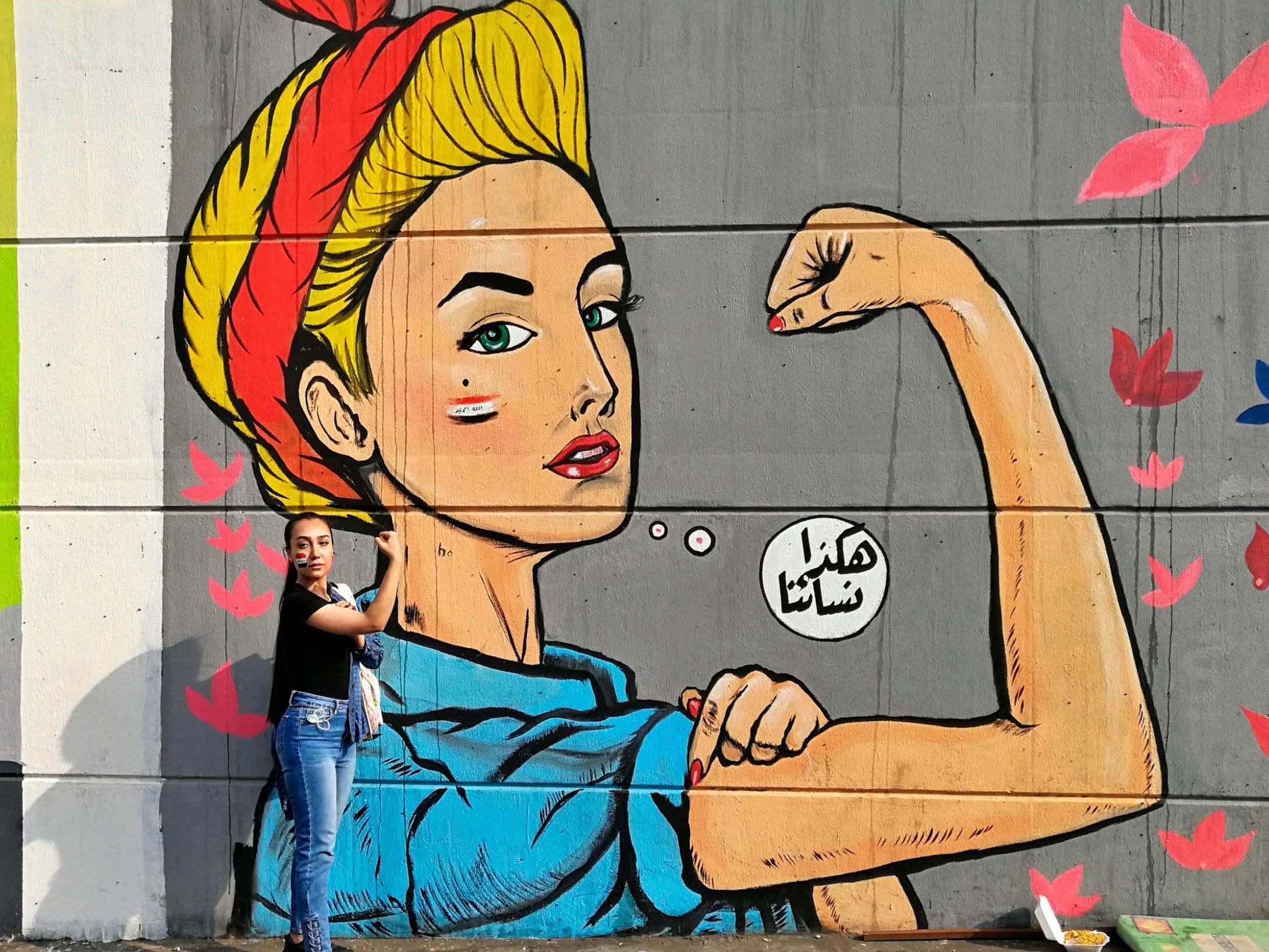 Woman poses for a photo in front of graffiti at the Saadoun tunnel, in Baghdad