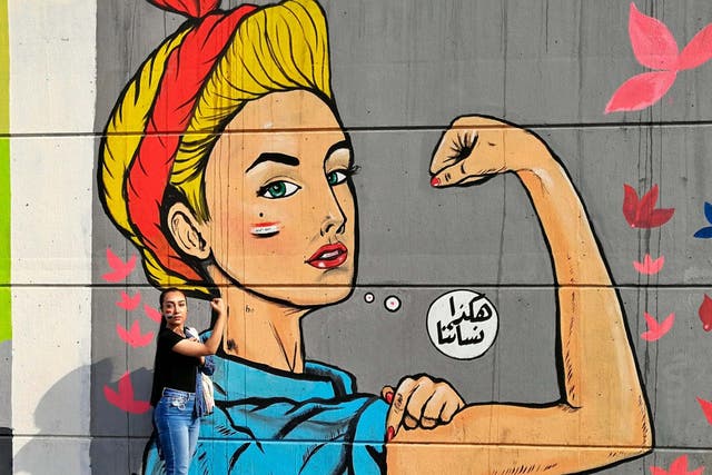 Woman poses for a photo in front of graffiti at the Saadoun tunnel, in Baghdad
