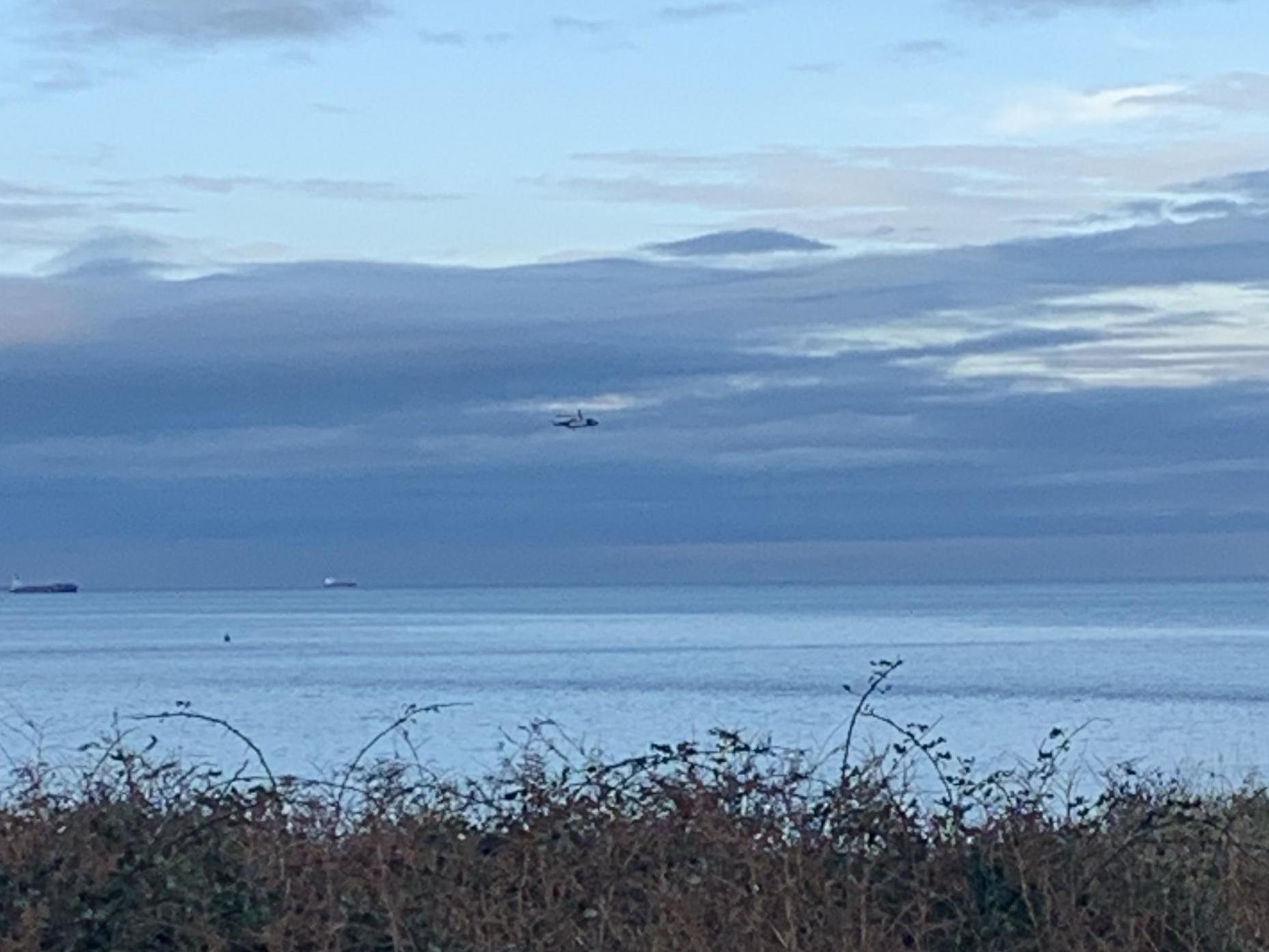 A helicopter joins the search following reports a light aircraft crashed in the sea near Anglesey