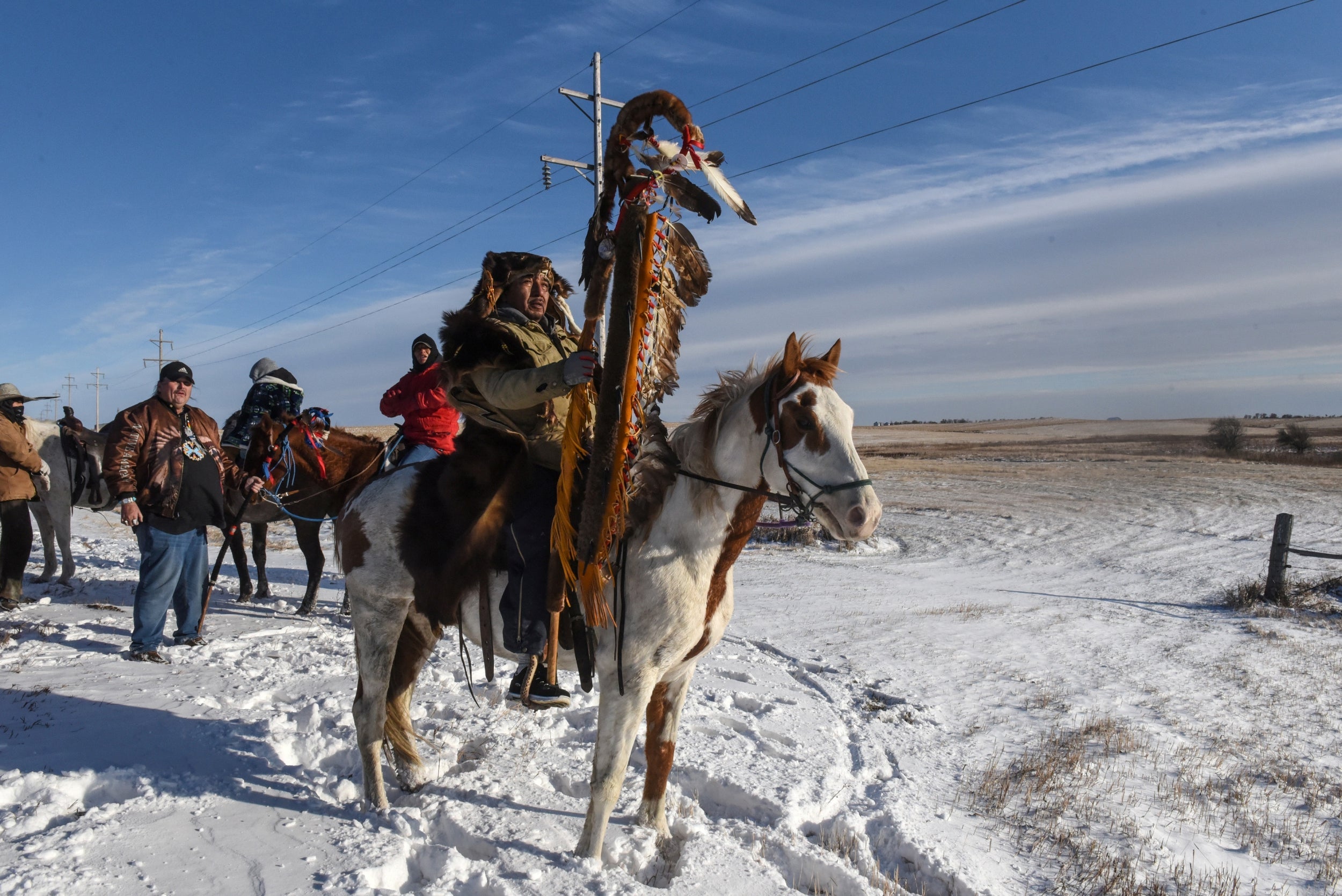 A Lakota member with a sacred staff rides to meet a descendant of the commander of the Wounded Knee massacre