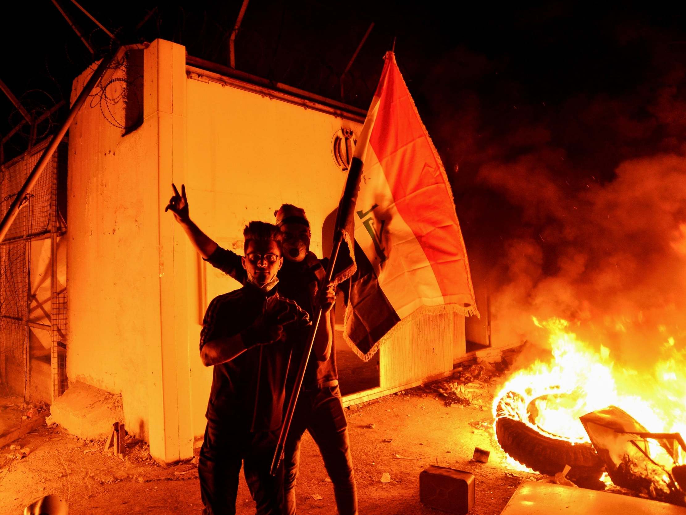 Iraqi demonstrators gesture as flames start consuming Iran’s consulate in the southern Iraqi Shia holy city Najaf