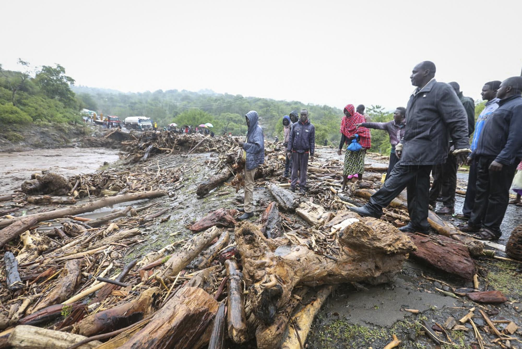 Passengers from stranded vehicles stand next to the debris from floodwaters, on the road from Kapenguria, in West Pokot county.