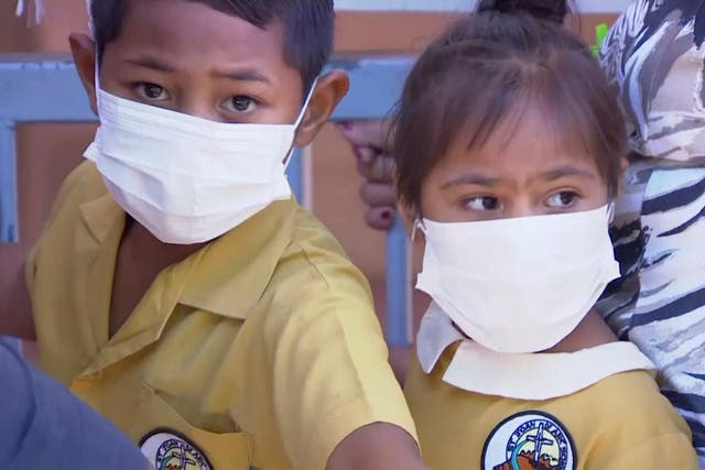 Masked children wait to be vaccinated at a health clinic in Apia, Samoa